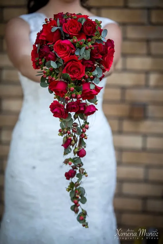 Bouquet da sposa a cascata lunga di rose rosse tenuto da una sposa