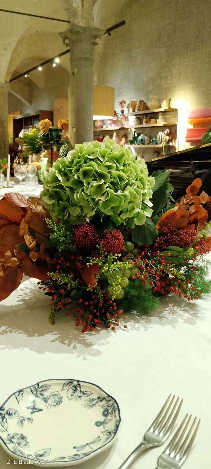 Centrotavola autunnale con ortensia verde, foglie ramate e bacche rosse